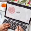 individual working on tax documents on laptop