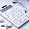 white calculator with coins on desk