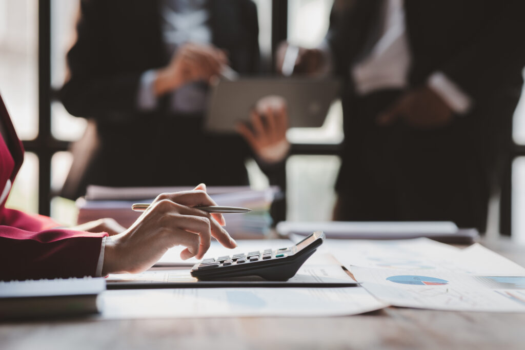 a person is using a calculator and reviewing financial reports to calculate the estimated chargeable income for a Singapore business