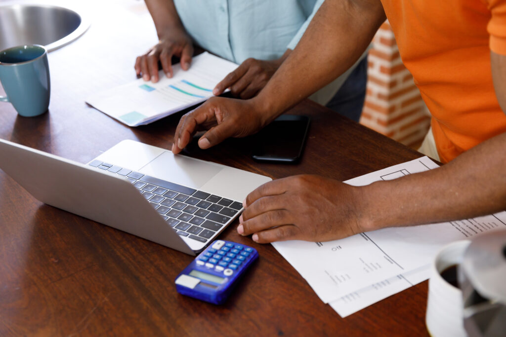 business partners working together at a table with a laptop, calculator, and financial documents to determine their estimated chargeable income in Singapore