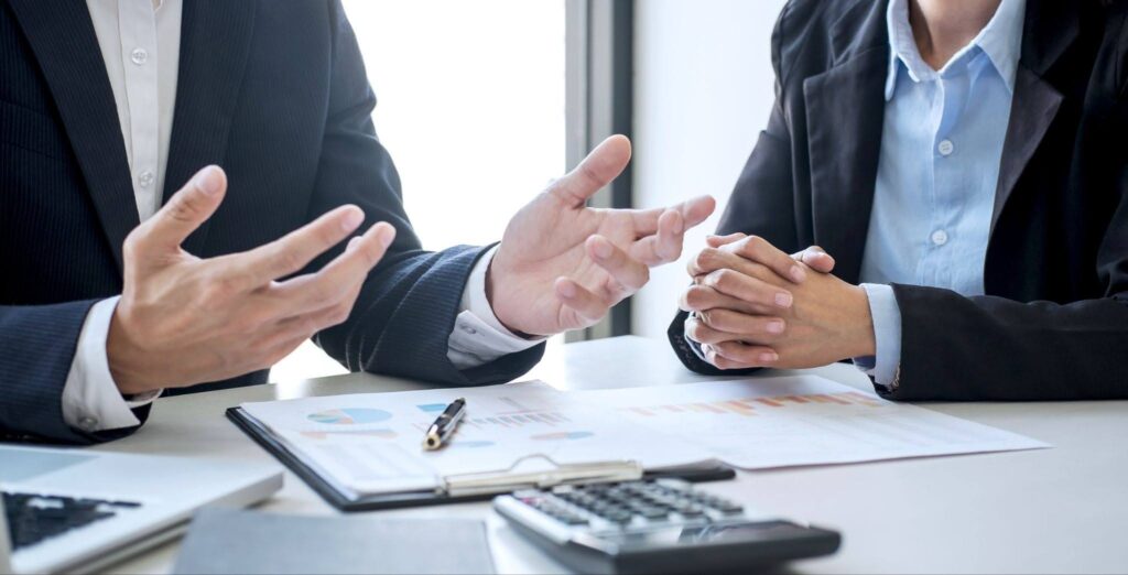 orporate advisors reviewing financial reports and bar graphs on a clipboard during a strategy session regarding the Start Up Tax Exemption Singapore (SUTE) for new businesses