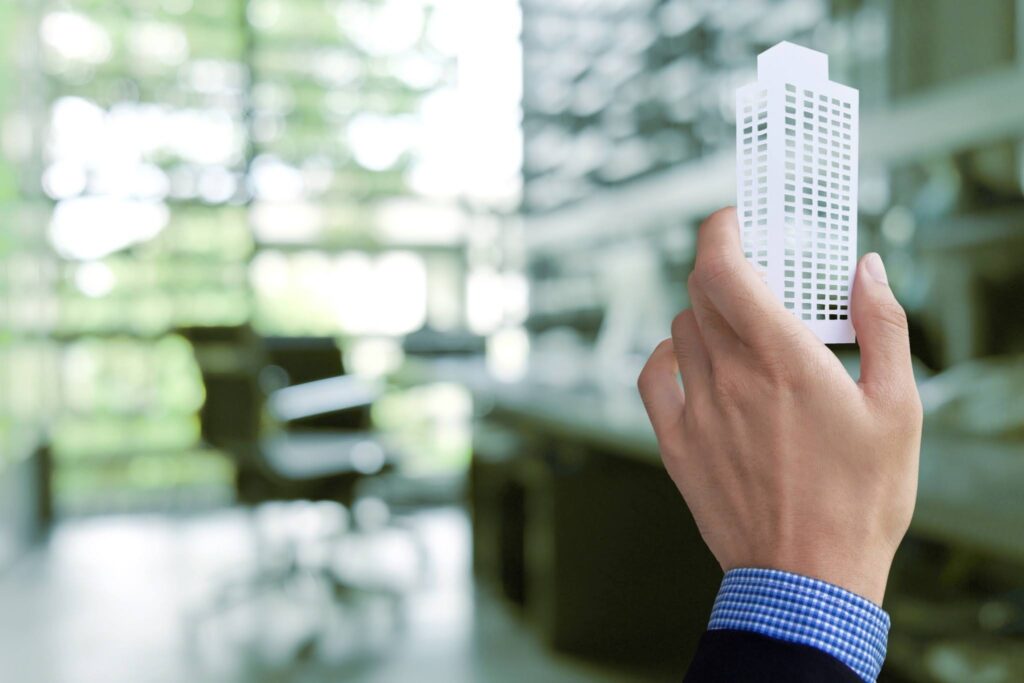 A close-up of a hand holding a paper office building model