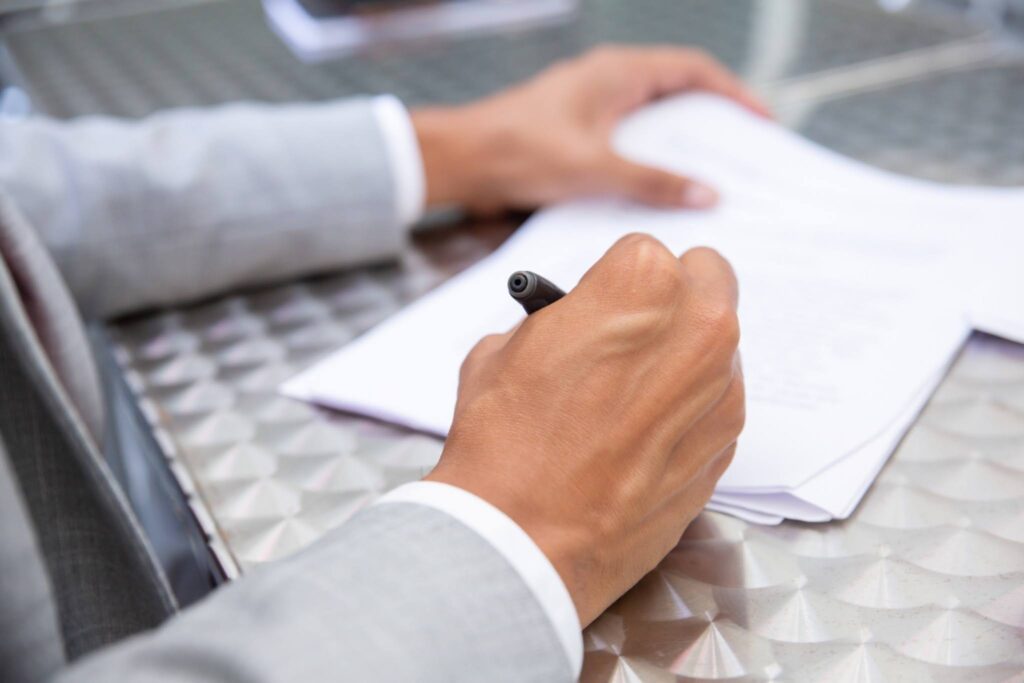 Close-up of a businessman in a grey suit signing the final legal documents to register a company in Singapore