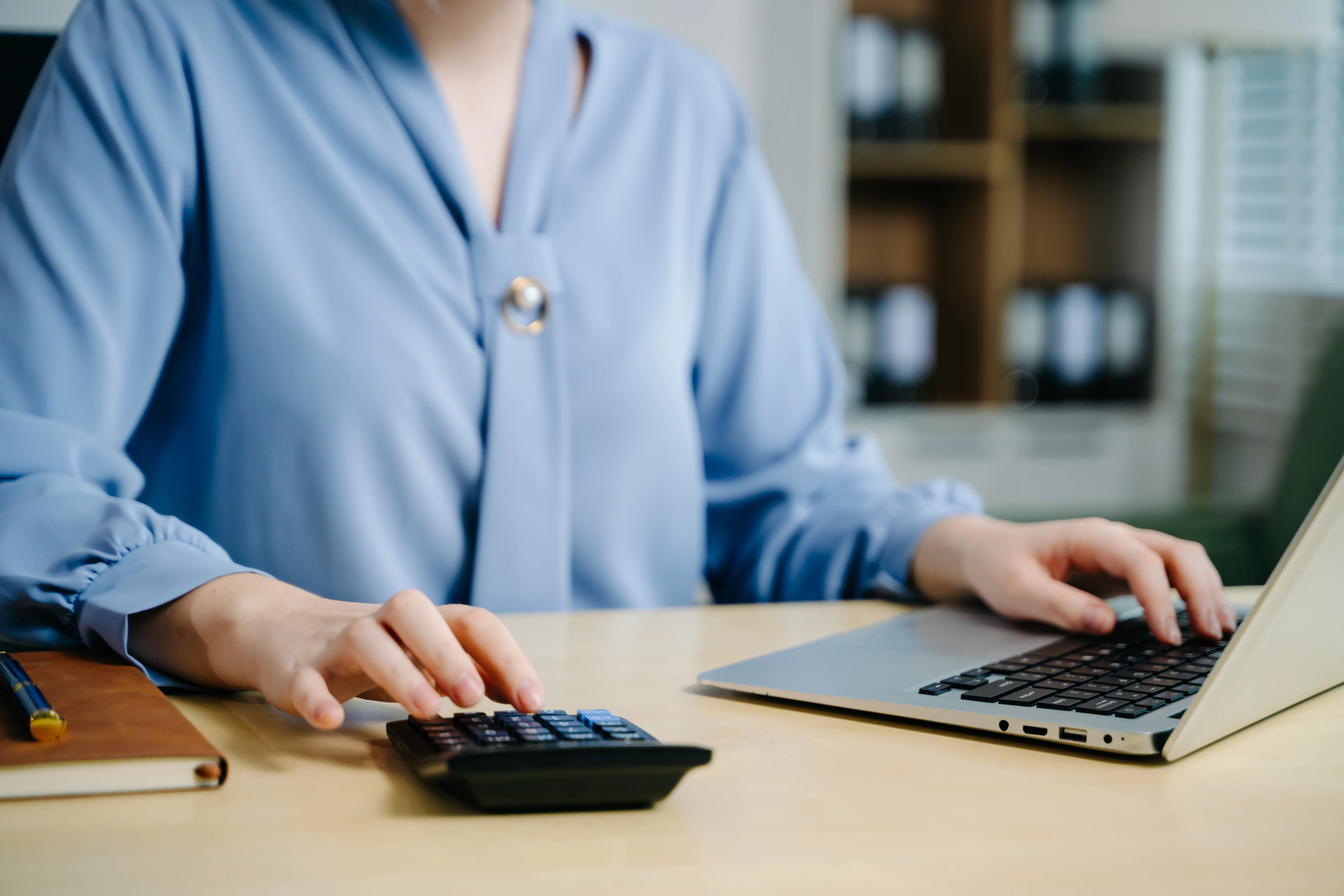 an accountant working at a desk using a laptop and a calculator