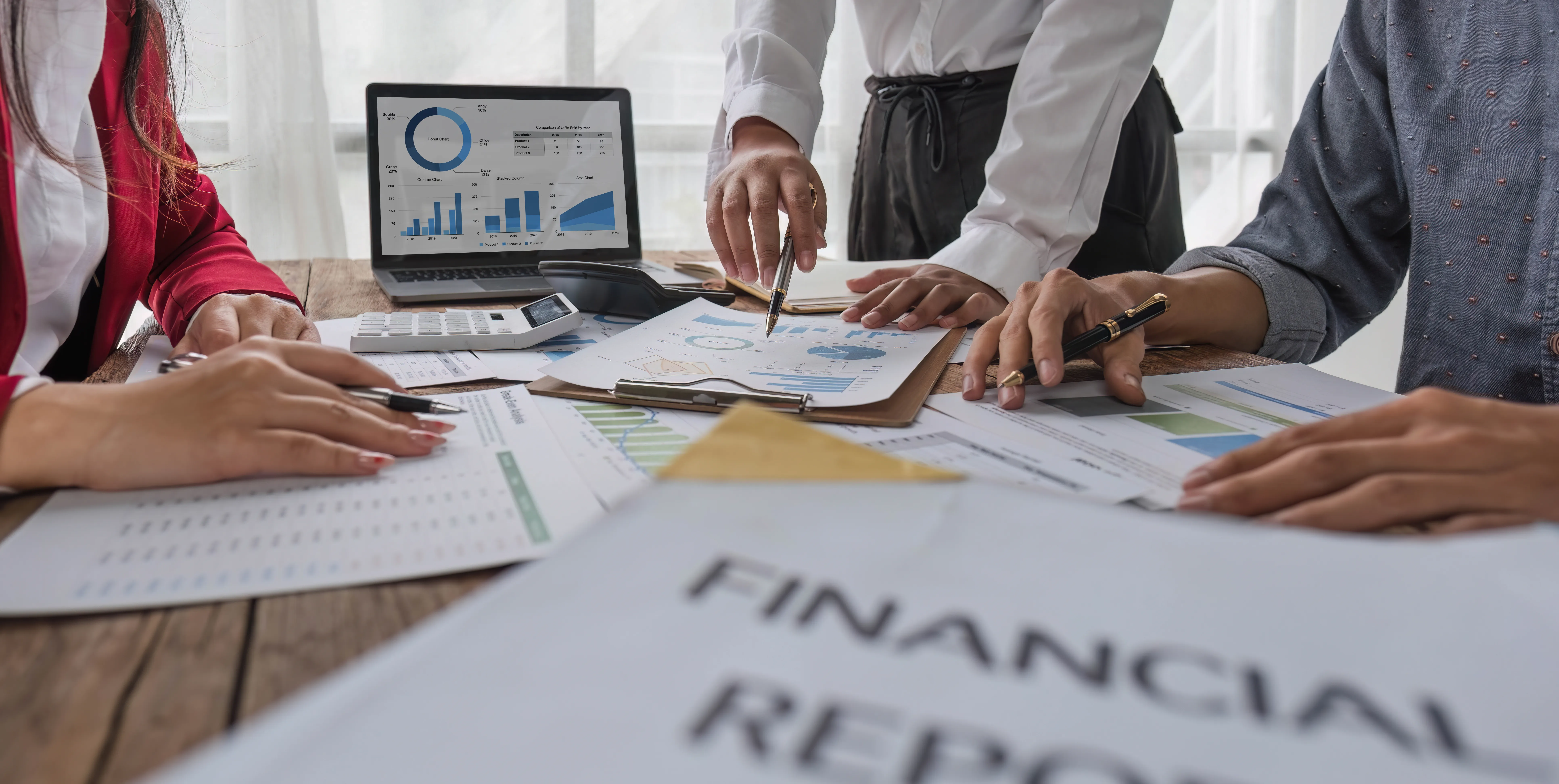 a business team reviewing financial charts and reports on charts and a laptop screen during a meeting
