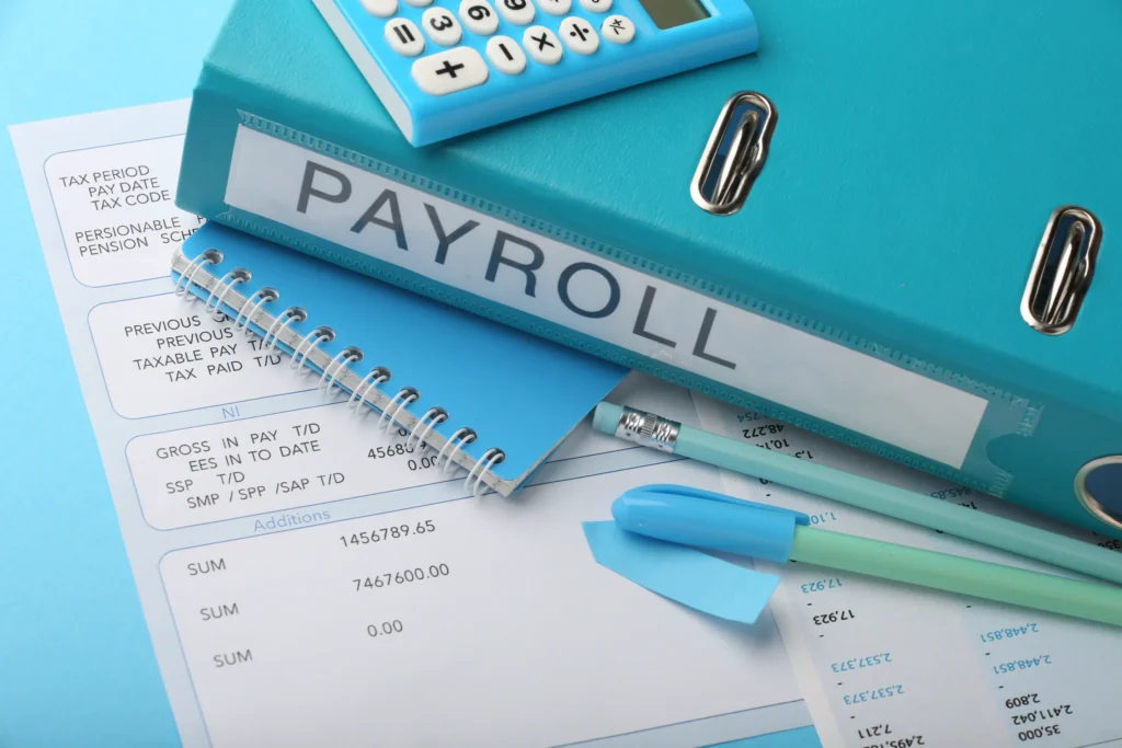 a blue office folder labeled payroll sitting on financial summary documents next to a calculator