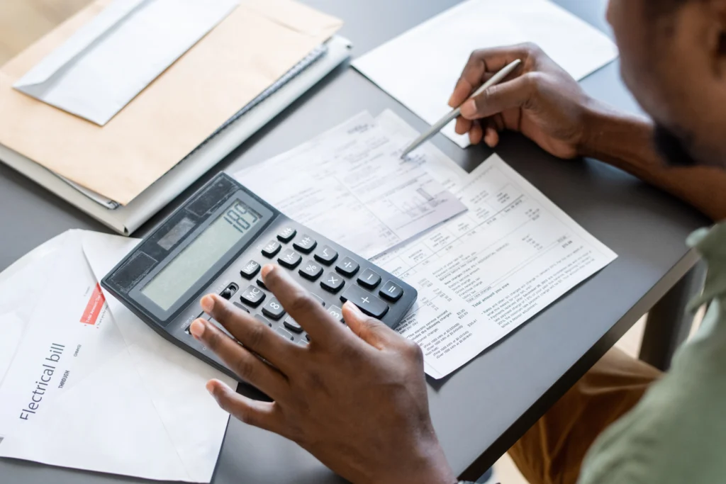 an individual reviewing financial documents using a calculator at a desk