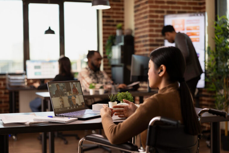 a business woman sitting in a modern office having a video conference call on her laptop